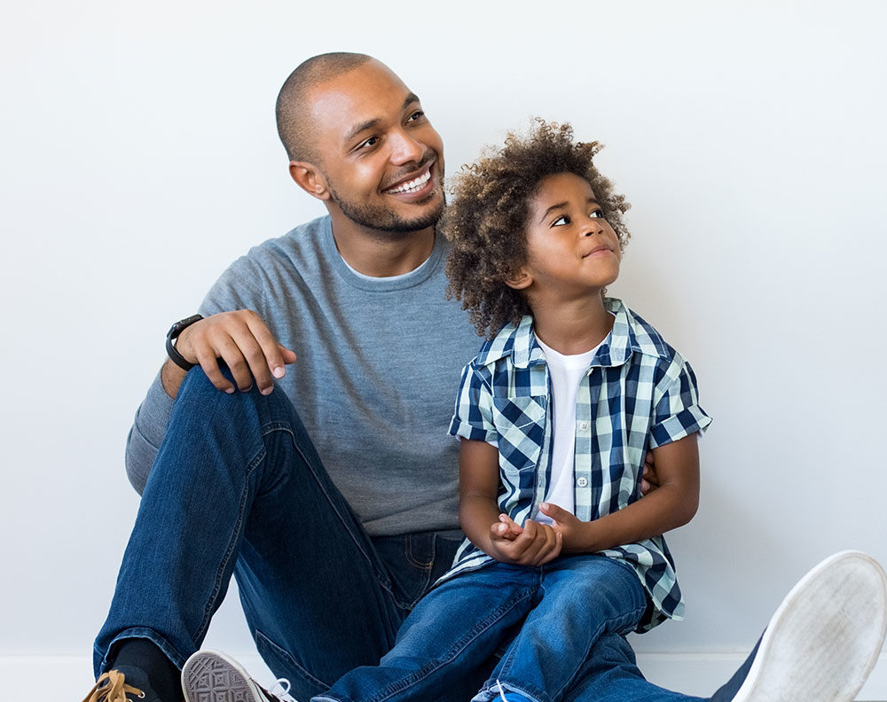 Father sitting on floor with son on his lap