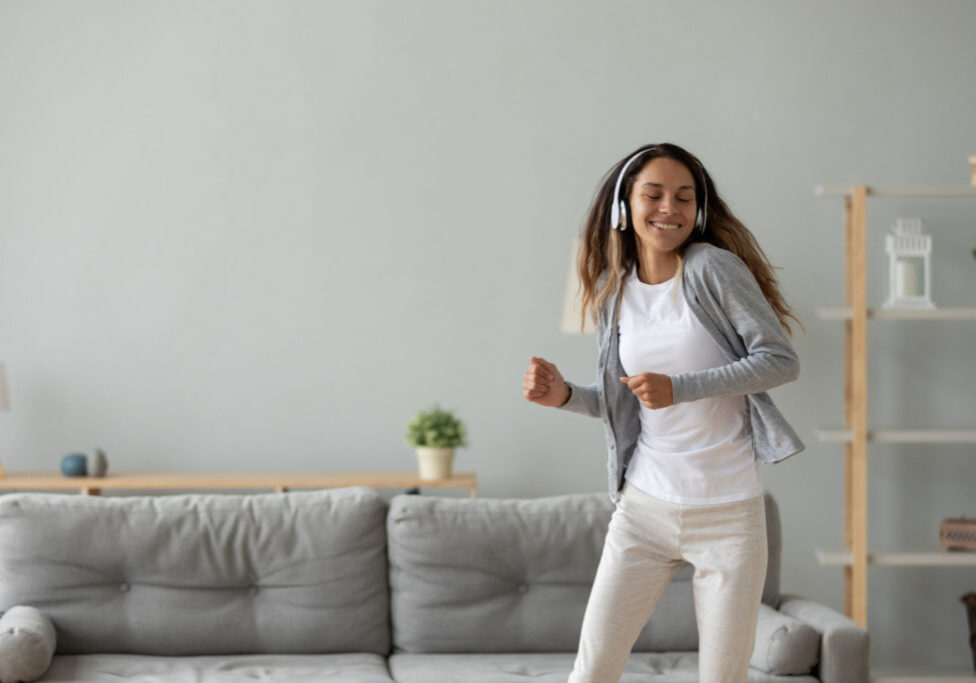 Overjoyed young woman listen to music dancing at home