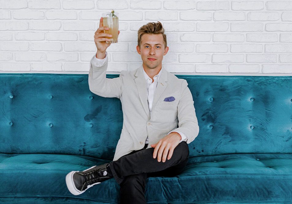 Man sitting on couch holding up beverage